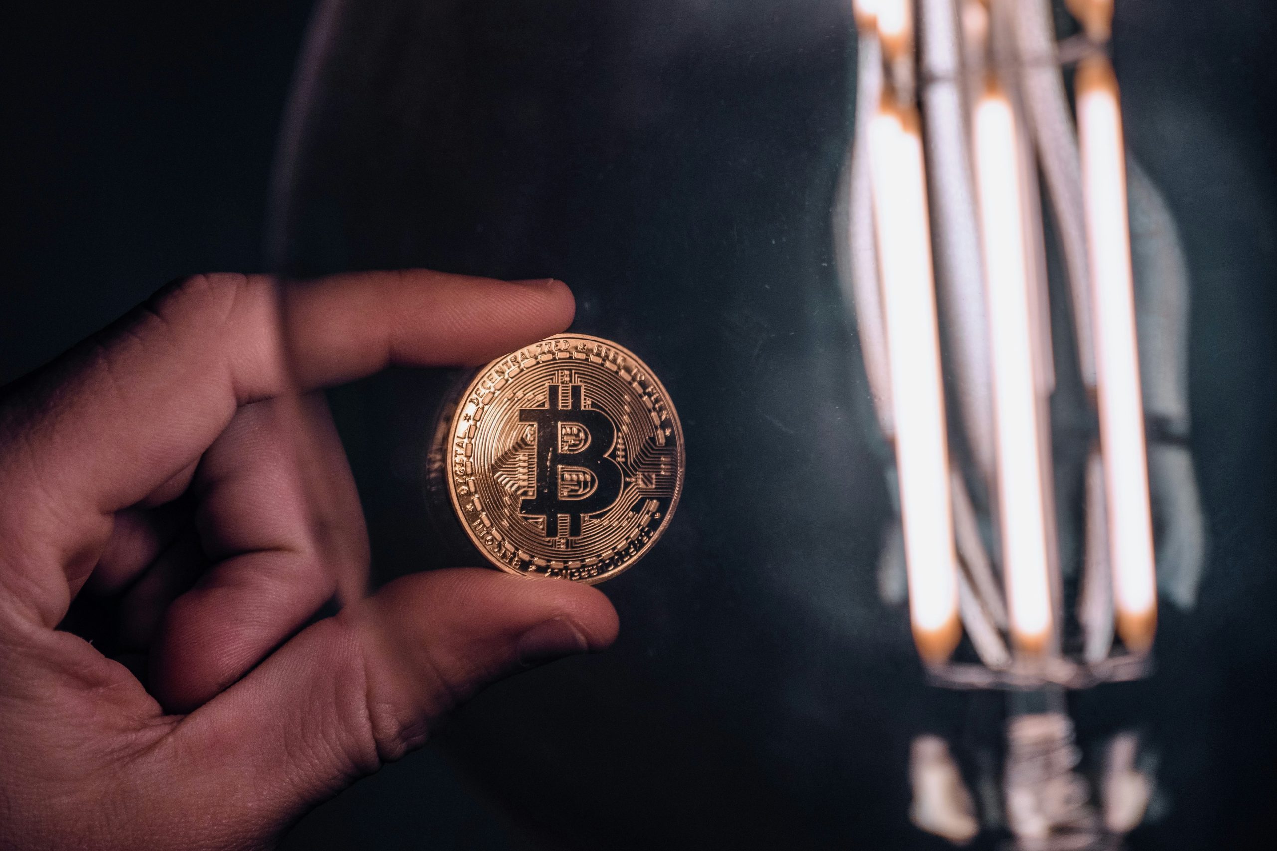 Một người đang cầm đồng Bitcoin vật lý, tượng trưng cho sự ra đời của tiền mã hóa phi tập trung đầu tiên trên thế giới vào năm 2008.