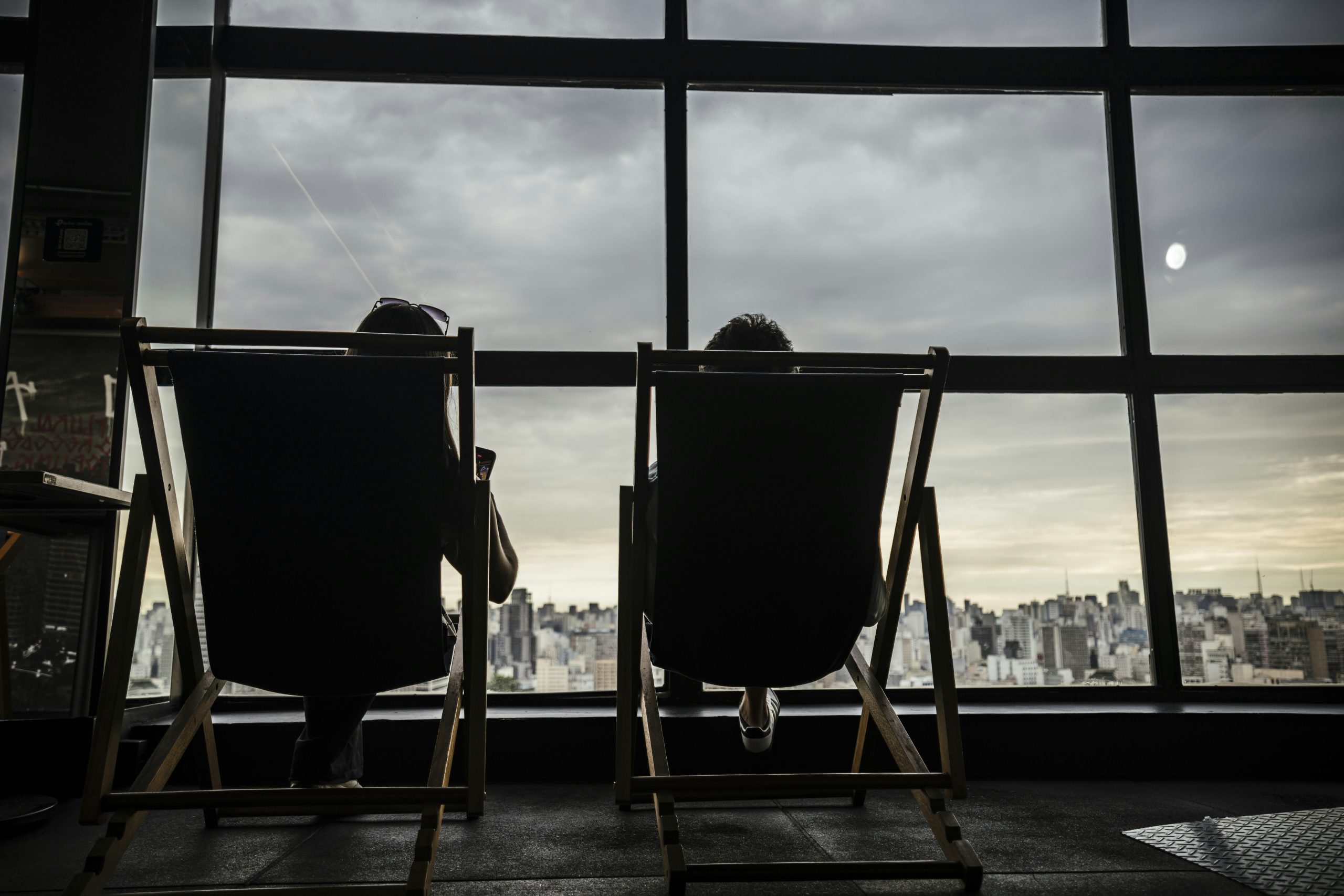 Người phụ nữ thư giãn trên ban công nhìn ra thành phố, tượng trưng cho tự do tài chính nhờ thu nhập thụ động từ bất động sản.