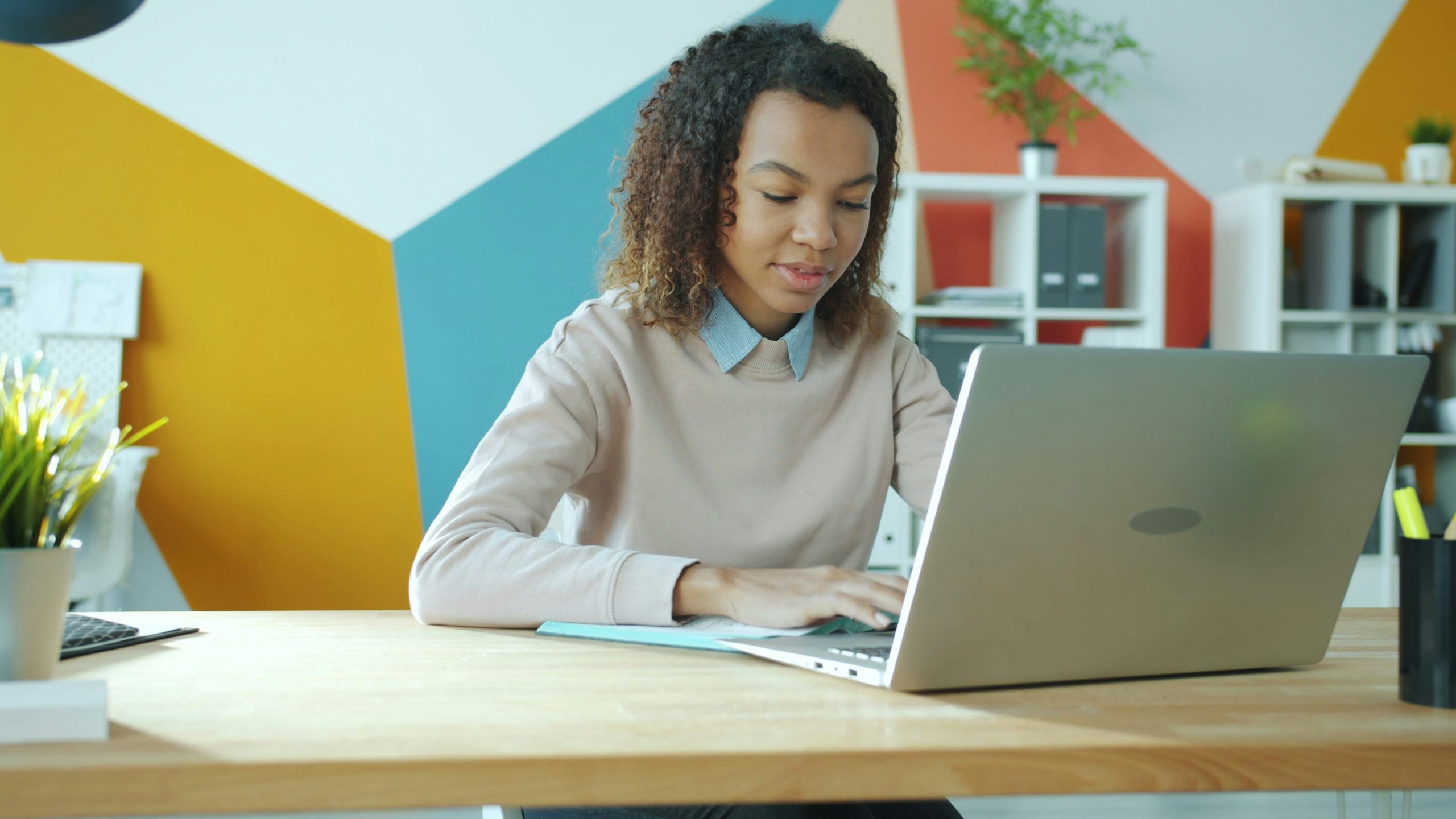 Bàn tay đang gõ bàn phím máy tính, trên màn hình hiển thị các biểu tượng công việc online như viết lách, thiết kế đồ họa, và quản lý mạng xã hội.